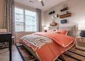Thumbnail 9 of 81 - A bedroom with a bed covered in an orange blanket.
