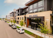 Thumbnail 1 of 81 - A street view of apartment buildings with cars parked on the side.