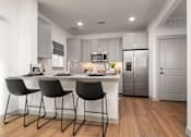 Thumbnail 16 of 52 - A modern kitchen with a white countertop and black barstools.