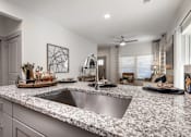 Thumbnail 18 of 52 - A modern kitchen with a granite countertop and stainless steel sink.