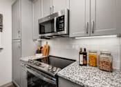 Thumbnail 17 of 52 - A modern kitchen with a stove top oven and microwave above it.