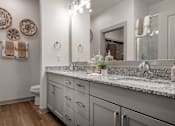 Thumbnail 26 of 52 - A bathroom with a marble countertop and a mirror above it.