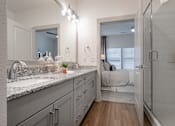 Thumbnail 25 of 52 - A bathroom with a sink, mirror, and a bedroom in the background.