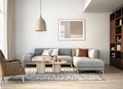Thumbnail 5 of 11 - A living room with a grey couch, a brown chair, and a wooden coffee table.