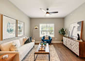 Thumbnail 28 of 33 - A living room with a white couch, a coffee table, and a ceiling fan at Beau Chene Lake Charles Apartments, Lake Charles