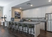 Thumbnail 8 of 12 - a clubhouse kitchen with a large island with bar stools and a stainless steel refrigerator at Beau Chene Lake Charles Apartments in Lake Charles, LA 70605