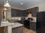 Thumbnail 12 of 12 - a kitchen with black appliances and granite counter tops at Beau Chene Lake Charles Apartments in Lake Charles, LA 70605