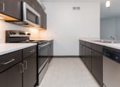 Thumbnail 20 of 81 - Modern open-concept kitchen and living area with stainless steel appliances.