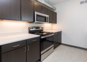 Thumbnail 21 of 81 - Modern open-concept kitchen and living area with stainless steel appliances.