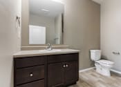 Thumbnail 26 of 54 - A bathroom with a white toilet and a vanity with a mirror.