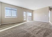 Thumbnail 23 of 54 - A large, empty room with carpeted flooring and a window with blinds.