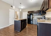 Thumbnail 33 of 54 - A kitchen with dark wood cabinets and a black refrigerator.