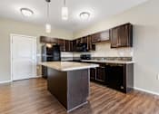 Thumbnail 35 of 54 - A kitchen with dark brown cabinets and black appliances.