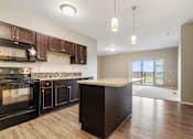 Thumbnail 37 of 54 - A kitchen with dark wood cabinets and a black oven.