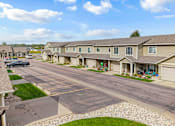 Thumbnail 5 of 64 - A residential street with houses on both sides and cars parked on the side.