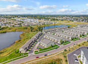 Thumbnail 61 of 64 - A large apartment complex sits next to a body of water with a road running through it.