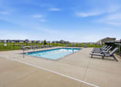 Thumbnail 57 of 59 - A pool surrounded by a black fence with sun loungers on the side.