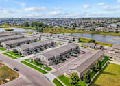 Thumbnail 6 of 64 - A large, modern housing complex with a lake in the background.