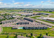 Thumbnail 15 of 31 - A large, modern building complex with a parking lot in front.