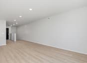 Thumbnail 11 of 68 - A large empty room with wooden flooring and white walls.