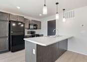 Thumbnail 19 of 68 - A modern kitchen with a black refrigerator and microwave, a white countertop, and wooden cabinets.