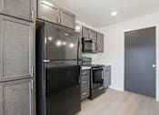 Thumbnail 17 of 68 - A black refrigerator is in a kitchen with wooden cabinets.