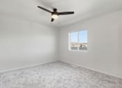 Thumbnail 13 of 68 - A room with a ceiling fan and a window with a view of the outside.