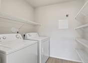 Thumbnail 23 of 68 - A laundry room with two washing machines and a shelf.