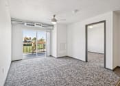 Thumbnail 5 of 21 - A room with a grey carpet and a sliding glass door leading to a balcony.