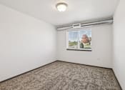 Thumbnail 8 of 21 - A room with a carpeted floor and a window showing a tree.