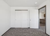 Thumbnail 10 of 21 - A room with white walls and a grey carpet with three white doors.