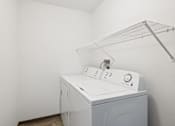 Thumbnail 11 of 21 - A white washing machine in a laundry room.