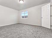 Thumbnail 40 of 60 - A room with a carpeted floor and a window.