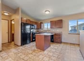 Thumbnail 9 of 64 - A kitchen with a black refrigerator and wooden cabinets.