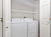 Thumbnail 43 of 60 - Two white washing machines in a small laundry room.
