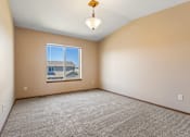 Thumbnail 35 of 64 - Empty room with a carpeted floor and a window showing a view of a house.