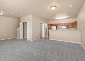 Thumbnail 12 of 40 - A spacious living room with a kitchen area in the background.