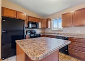 Thumbnail 1 of 64 - A kitchen with a granite countertop and wooden cabinets.