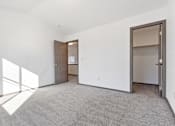 Thumbnail 17 of 47 - A large, empty room with a carpeted floor and a door on the right side.