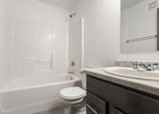 Thumbnail 31 of 59 - A white toilet sits next to a white bathtub in a bathroom.