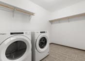 Thumbnail 34 of 59 - Two white front loading washing machines in a laundry room.