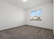 Thumbnail 35 of 59 - A room with a carpeted floor and a window showing a view of houses.
