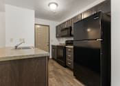 Thumbnail 38 of 59 - A kitchen with a black refrigerator and wooden cabinets.
