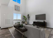 Thumbnail 5 of 57 - A living room with a grey couch, a coffee table, and a flat screen TV.