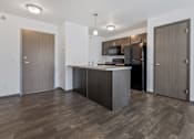 Thumbnail 18 of 57 - A kitchen with a black refrigerator and wooden floors.