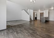 Thumbnail 17 of 57 - A spacious room with wooden flooring and a kitchen area in the background.
