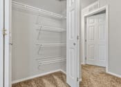 Thumbnail 48 of 60 - A white pantry with a carpeted floor and a white door.