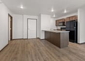 Thumbnail 28 of 44 - A kitchen with a black refrigerator and wooden floors.