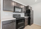 Thumbnail 24 of 68 - A kitchen with black appliances and wooden cabinets.