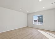 Thumbnail 27 of 68 - A large empty room with a window showing a house and a white floor.